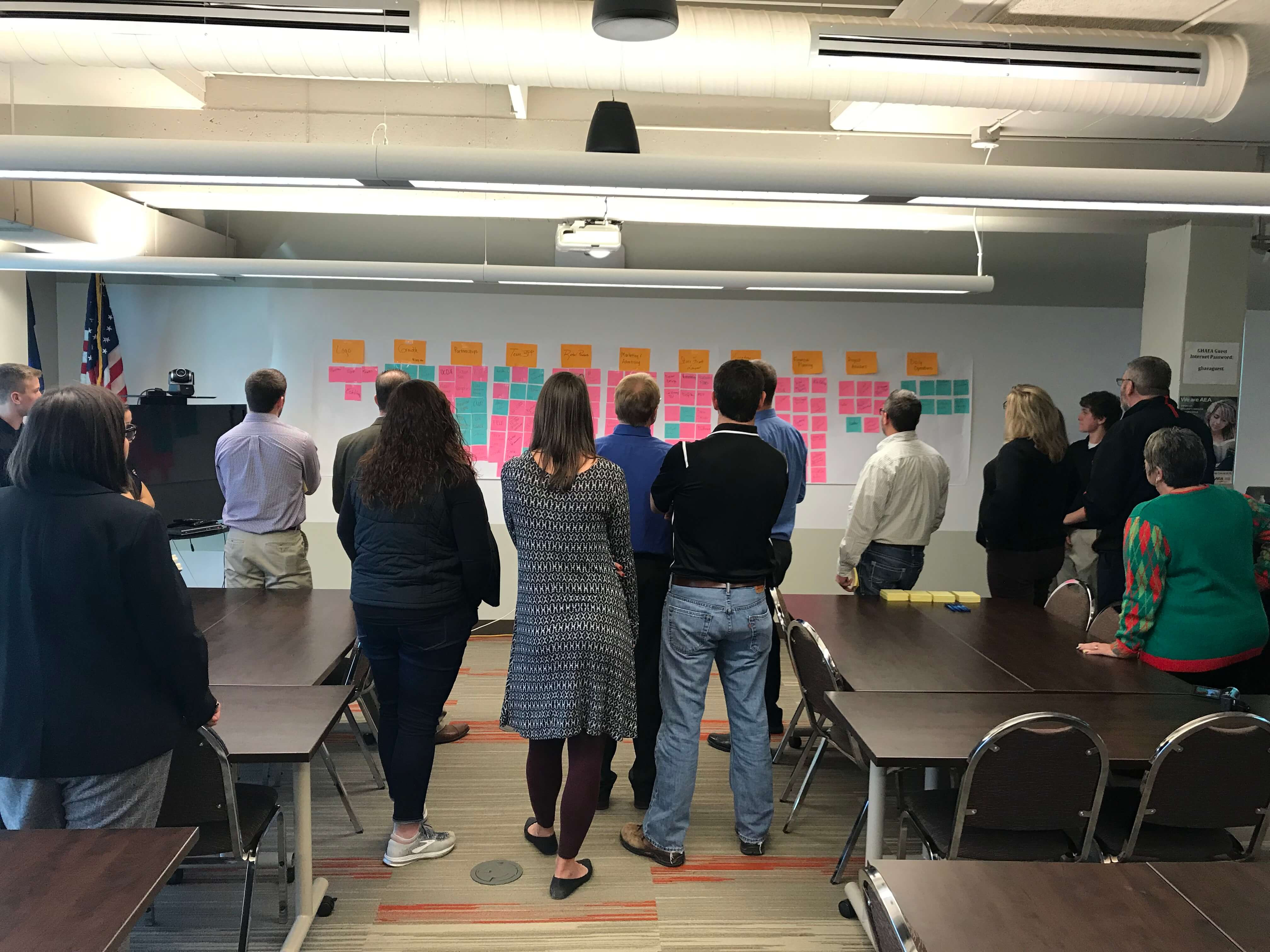 teachers face a project board with sticky notes on the wall